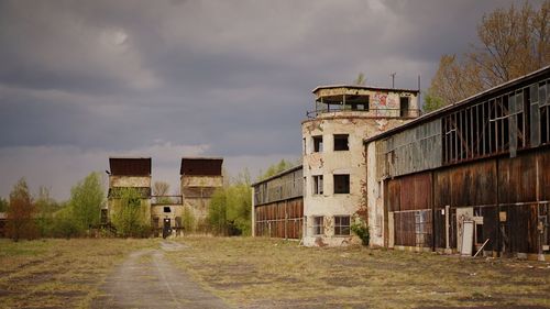 Road by old factory against cloudy sky