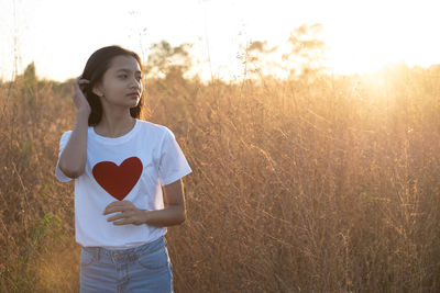 Mid adult woman standing on field against sky during sunset