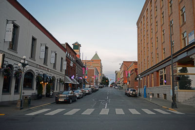 Road amidst buildings in city against sky