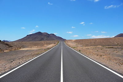 Road amidst desert against sky