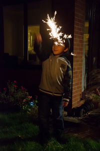 Boy standing by illuminated light at night