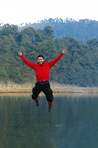 Full length of man jumping against lake