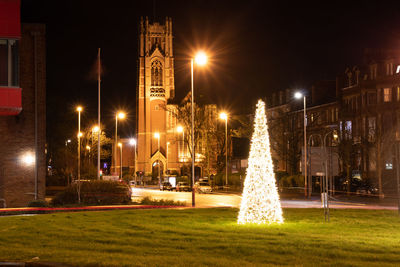 Illuminated street light by building at night