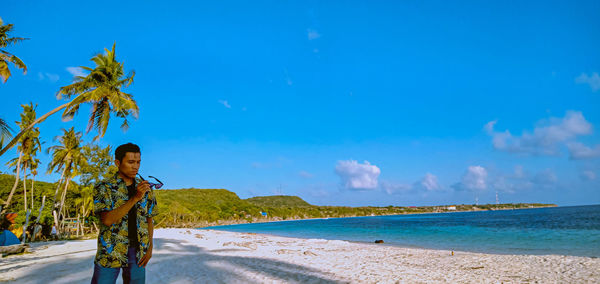 Man standing at beach against blue sky