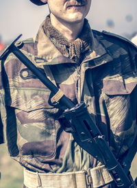 Midsection of soldier standing while carrying gun