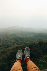 Low section of man wearing shoes against landscape