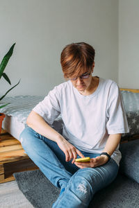 Woman with short hair at home sitting on the floor with her smartphone