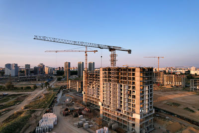 Cranes at construction site in city against clear sky