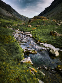 Scenic view of stream amidst rocks against sky