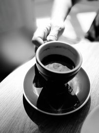 Close-up of hand holding tea cup on table