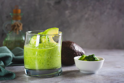 Green smoothie from avocado and cucumbers in a glass on the table
