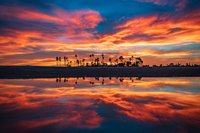 Scenic view of lake against dramatic sky during sunset