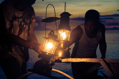 Man holding woman standing by boat against sky during sunset