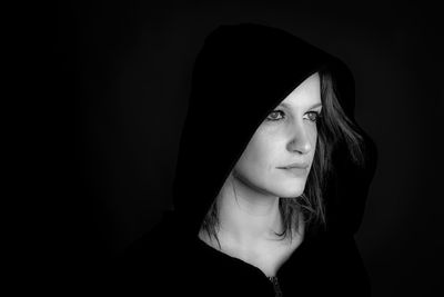 Close-up of thoughtful woman against black background