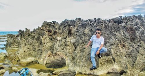 Man standing on rock against sky