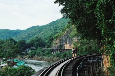 Rear view of man walking on mountain by road against sky