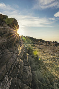 Rock formations on landscape against sun