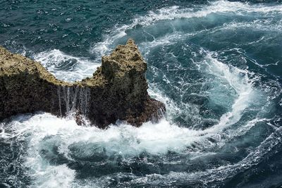 High angle view of wave splashing on rock formation in sea