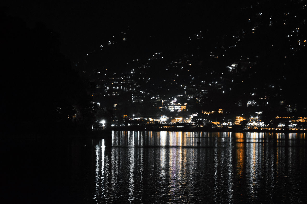 ILLUMINATED CITY BY RIVER AGAINST SKY