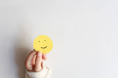 Cropped hand holding red heart shape against white background