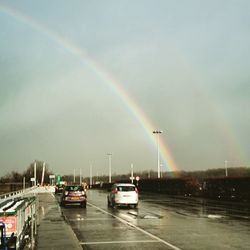 Cars on road against cloudy sky