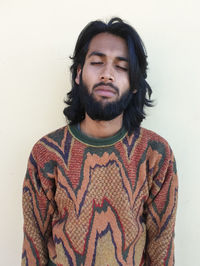 Portrait of young man standing against white background