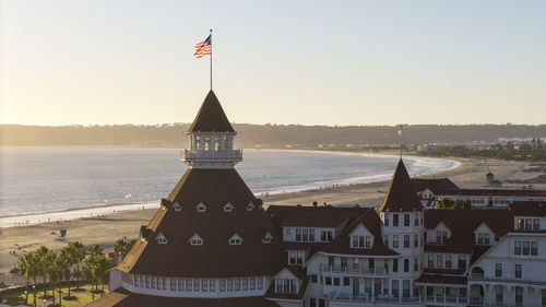 Houses by sea against sky during sunset