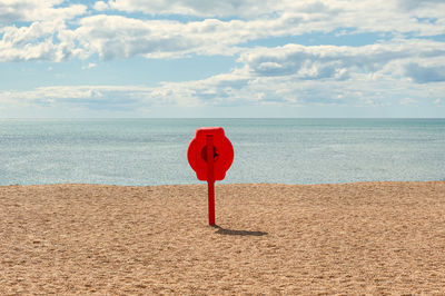 Red umbrella on beach against sky