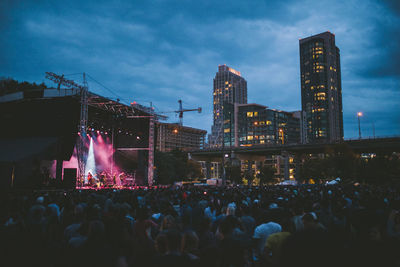 Crowd at illuminated city against sky at dusk