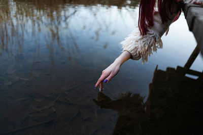 Rear view of woman standing by lake