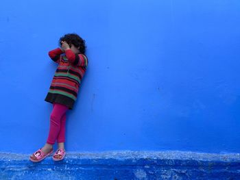 Girl standing against blue wall