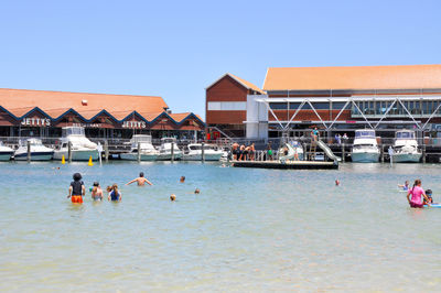 People on shore against clear sky