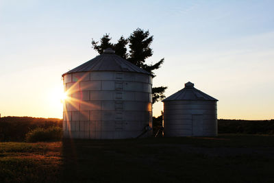 Silos against sky during sunset