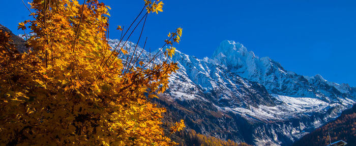 Low angle view of snowcapped mountains against clear blue sky