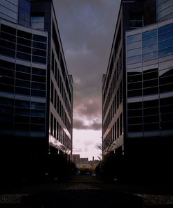 Road by buildings against sky at sunset