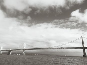 Suspension bridge against cloudy sky