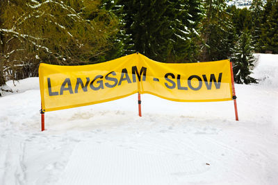 Information sign on snow covered field against trees in forest