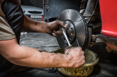 Midsection of mechanic repairing car in garage