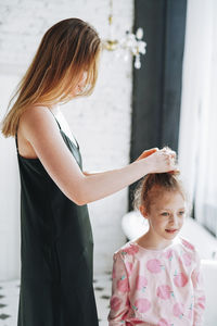 Young mother woman in black dress and little tween girl daughter having fun in the morning at home