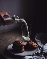 Cropped hand pouring milk from bottle in glass