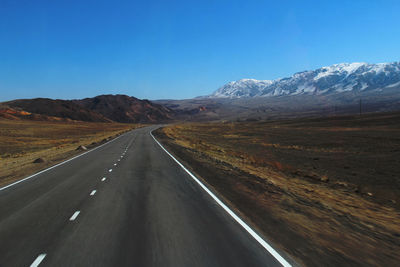 Highway with a turn in the mountains with a snow-covered mountain range, spring, sunny, day