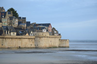 Buildings by sea against sky