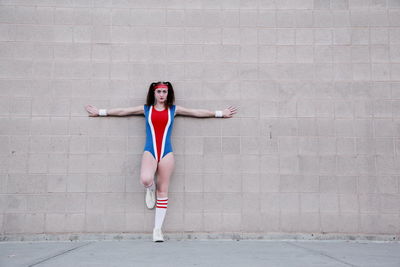 Full length portrait of teenage girl wearing uniform while standing against wall