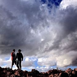 Man standing on mountain against cloudy sky