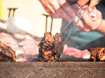 Close-up of person preparing food on barbecue grill