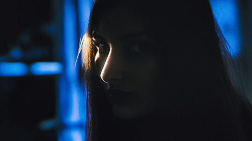 Close-up portrait of young woman in darkroom