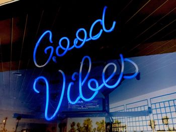 Low angle view of illuminated text against blue sky at night