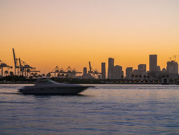 Scenic view of sea by buildings against sky during sunset