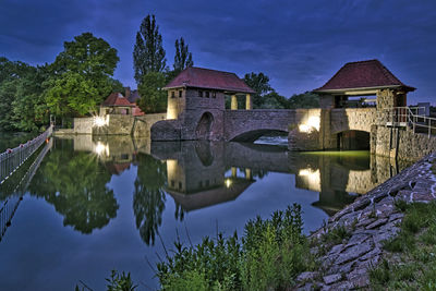 Houses by lake against sky at night