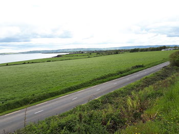 Road amidst field against sky